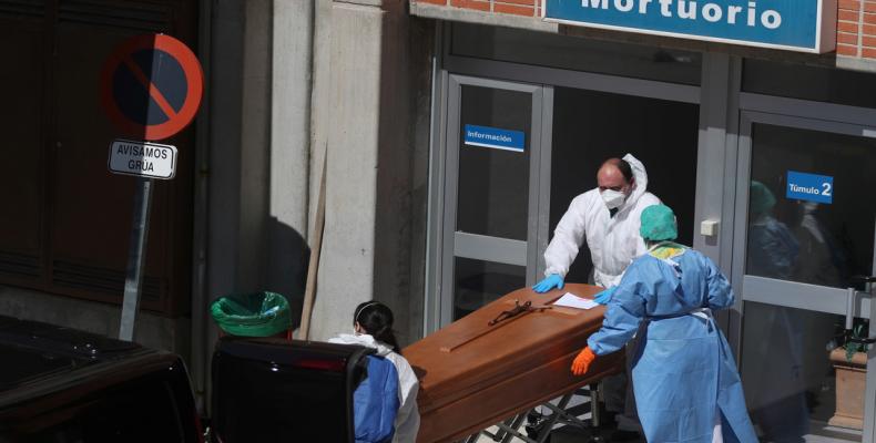 Trabajadores funerarios con trajes protectores sacan un ataúd de la morgue en medio de la pandemia en el Hospital Severo Ochoa, en Leganés, España, 26 de marzo