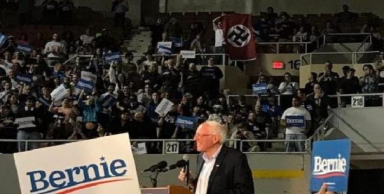 Un asistente provoca a Bernie Sanders con una bandera nazi. Foto: Agencias.