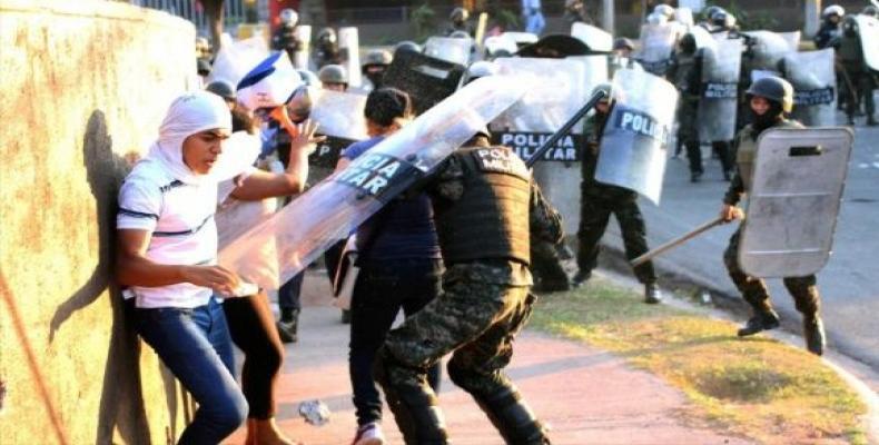 Policías arremetiendo contra manifestantes hondureños