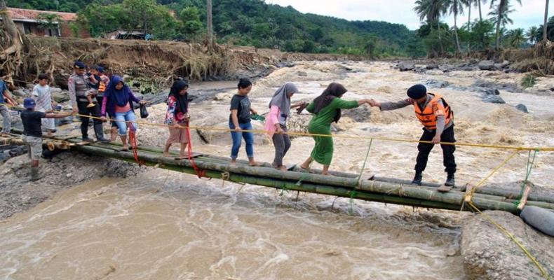 Police help people to get through an emergency bridge in Bogor.  (Photo: Antara Foto/Arif Firmansyah/via Reuters) 