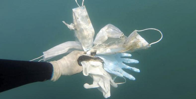 Foto del 21 de mayo, proporcionada por el grupo ambientalista Operation Mer Propre (Operación mar limpio) de un buzo sosteniendo guantes y mascarillas encontrad