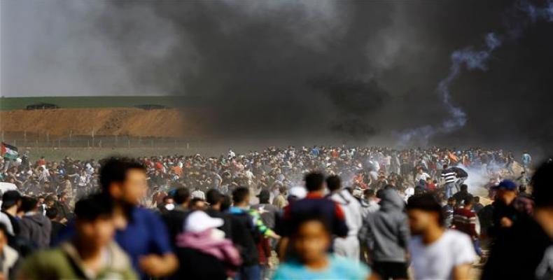 Palestinians run for cover from tears gas fired by Israeli forces during clashes following a protest on the Israel-Gaza border east of the Jabalia refugee camp