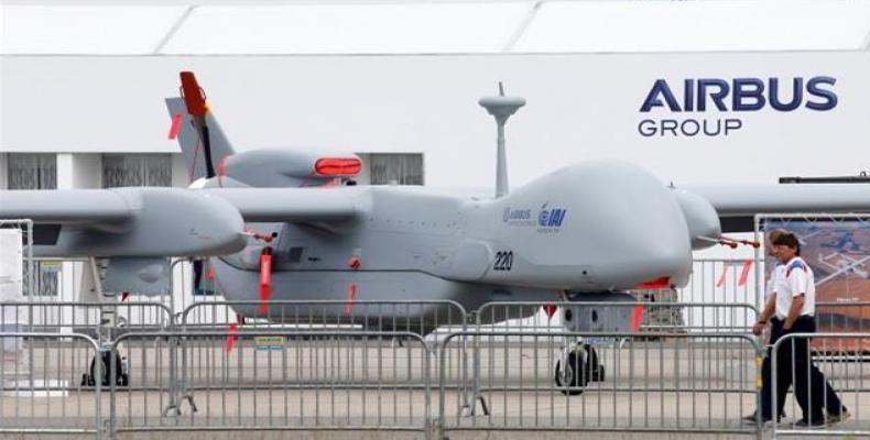Visitors walk past a surveillance unmanned air vehicle (UAV) 'Heron TP' by IAI and Airbus Defence at the ILA Berlin Air Show in Schoenefeld, south of Berlin, Ma