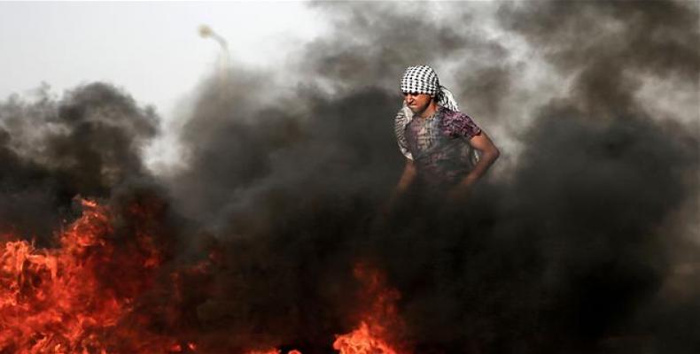 A Palestinian demonstrator walks in the smoke billowing from burning tires during clashes with Israeli forces along the border with the Gaza strip east of Gaza