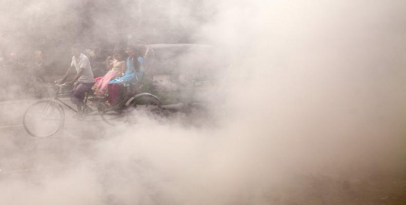 A Bangladeshi rickshaw puller rides past smoke created by burning waste materials on a street in Dhaka. Photograph: Anadolu Agency/Getty Images 