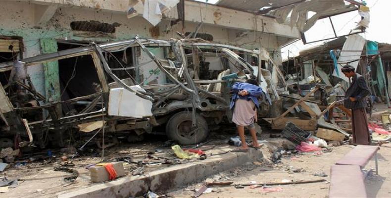 Yemenis gather next to a destroyed bus at the site of a Saudi-led airstrike that targeted the Dhahyan market the previous day in Sa’ada province, Yemen, on Augu