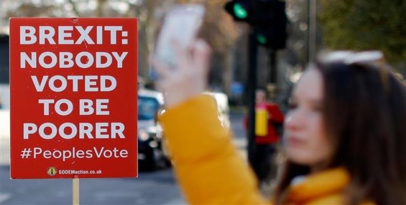 A tourist takes a photograph of the Houses of Parliament, near an anti-Brexit campaigner's placard, in central London, on December 17, 2018.  Photo: AFP