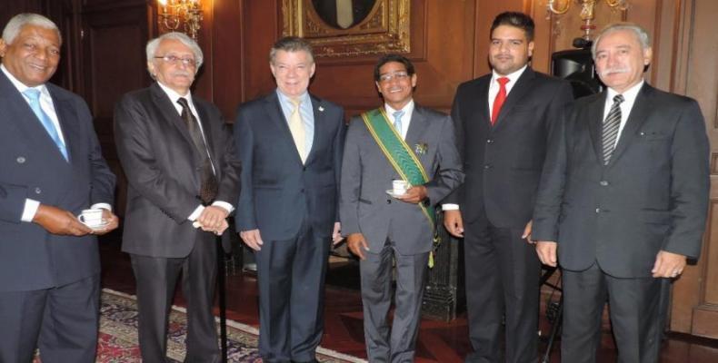 Iván Mora (green band) with former President Juan Manuel Santos.  They are accompanied by the current Cuban ambassador, José Luis Ponce.