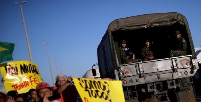 A truck carrying army officials passes by people supporting the truck owners striking in protest against high diesel prices in Luziania, Brazil May 27, 2018.  P