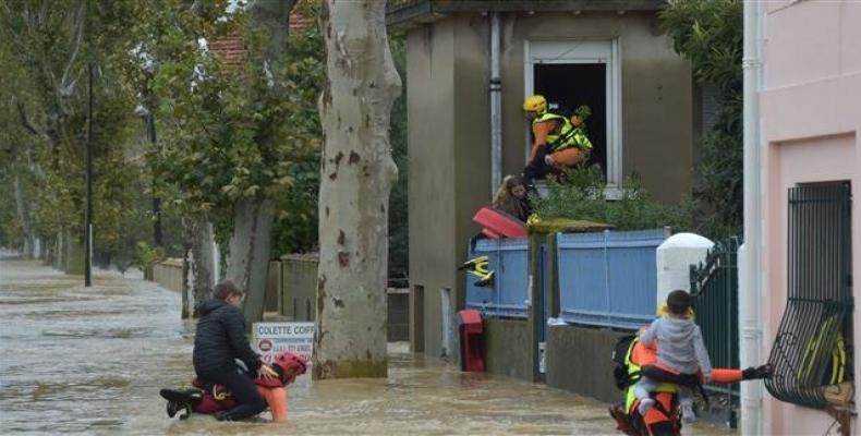 Firefighters help youngsters evacuate in a flooded street during a rescue operation following heavy rains that saw rivers bursting banks on October 15, 2018 in