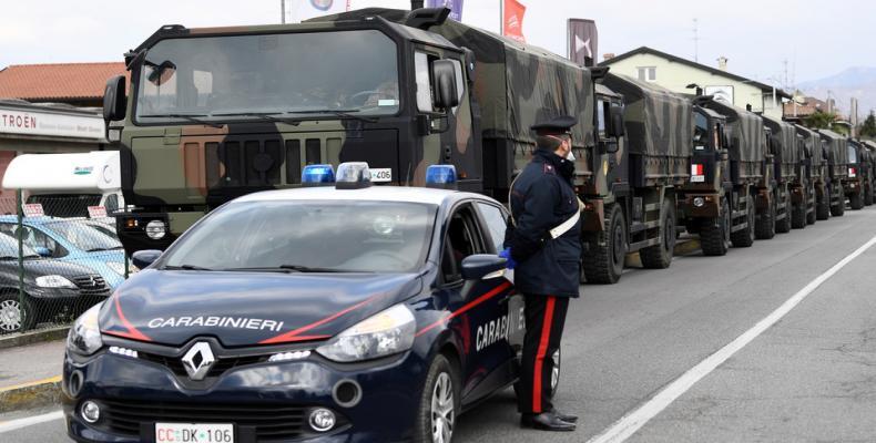 Carabinieri military police officer stands guard as military trucks wait to take away coffins in Seriate, Italy.  (Photo: REUTERS/Flavio Lo Scalzo)