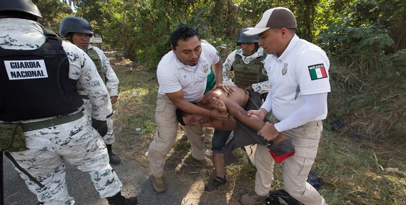 Immigration officials and Mexican National Guard troops force a man towards a bus.  (Photo: Jeff Abbott/Al Jazeera)