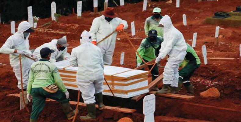 Workers bury a coffin in a grave at a cemetery for coronavirus victims in Jakarta, Indonesia.  (Photo: Reuters)
