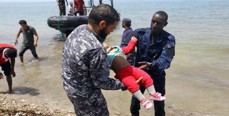 Members of Libyan security forces carry the body of a baby as refugees who survived the sinking of an inflatable dinghy off the coast of Libya are brought ashor