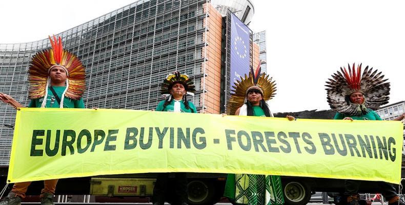 Brazilian indigenous community leaders hold a sign during a protest against the destruction of the Amazon forest, outside the European Commission headquarters