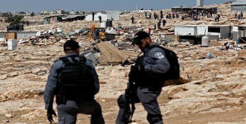 Israeli police officers secure a bulldozer demolishing structures in the Palestinian Bedouin village of Khan al-Ahmar east of Jerusalem in the occupied West Ban