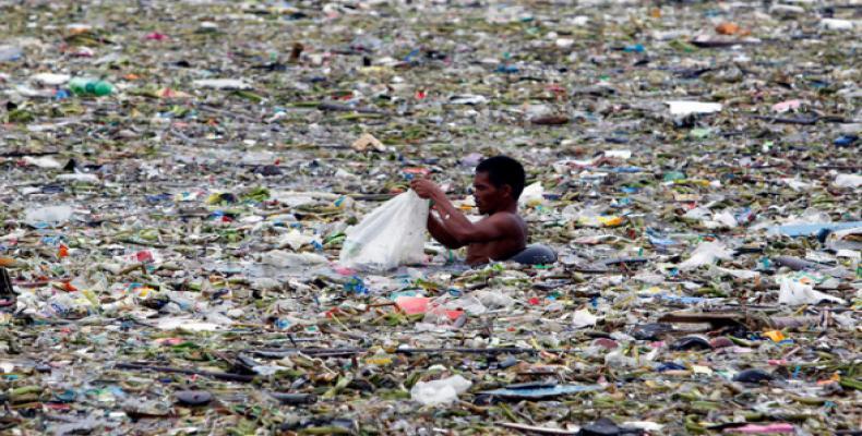 A man collects plastic and other recyclable materials from debris in the waters of Manila Bay in Manila, Philippines. Mismanaged waste from land is the primary