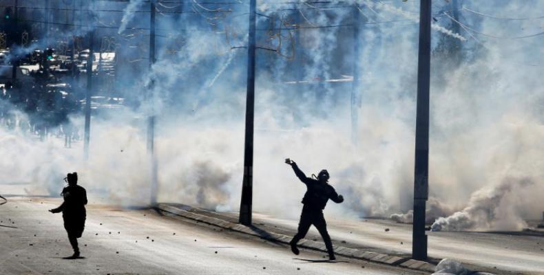 A Palestinian protester hurls stones as tear gas is fired by Israeli troops during clashes in the West Bank city of Bethlehem. (Reuters)