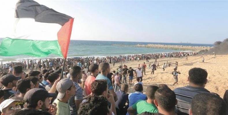 Palestinian protesters wave national flags as they participate in a demonstration on the beach near the maritime border with Israel, in the northern Gaza Strip,