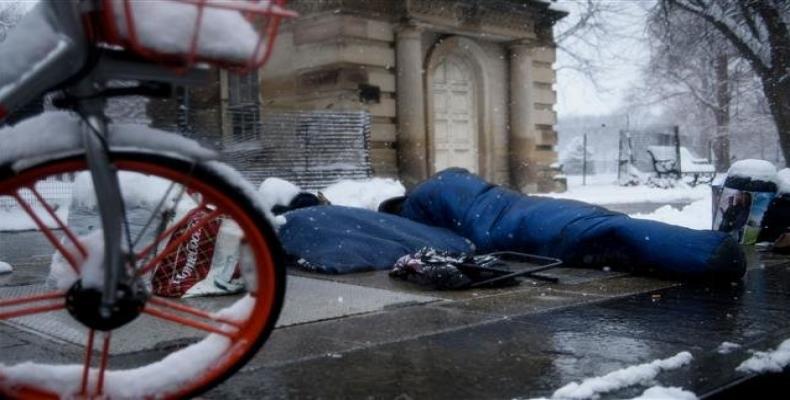 A homeless man rests above a warm air vent near the White House during a winter storm January 13, 2019 in Washington, DC.  Photo: AFP