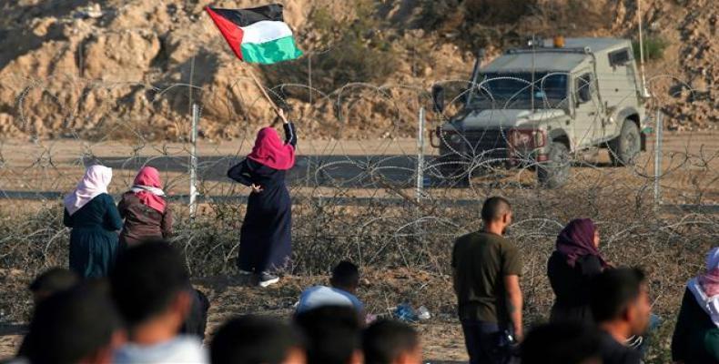 A Palestinian protester waves her flag during a demonstration along the fence with the occupied territories in central Gaza Strip.  (Photo: AFP)