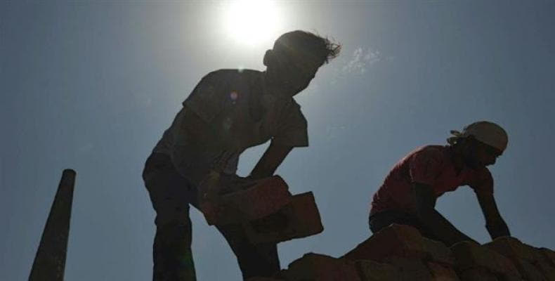 This photograph taken on September 16, 2017, shows Indian laborers loading bricks onto a tractor trolley at a brick kiln on the outskirts of Amritsar.  Photo: A