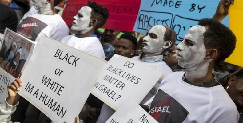 African migrants demonstrate with white paint on their faces outside the Embassy of Rwanda in Israel on February 7, 2018, against an Israeli plan to forcibly