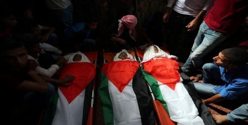 Mourners gather around the bodies of Palestinian boys who were killed in an Israeli air strike on the Gaza Strip frontier, during their funeral in the central G