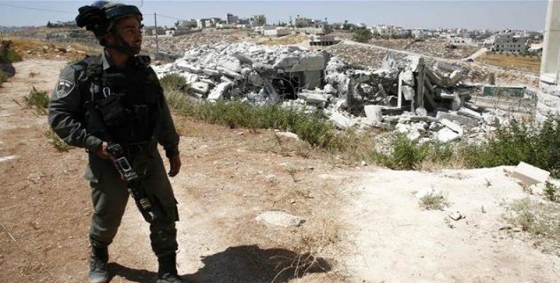 Israeli policeman stands in front of demolished buildings.  (Photo: AFP)
