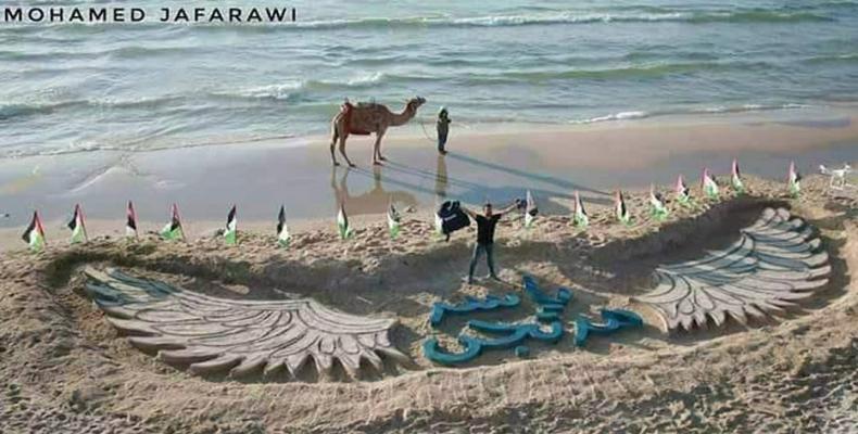  Palestinian activists carve Yaser Murtajas name in Gazan sand.  Photo: AP