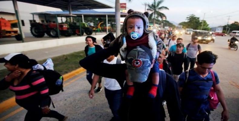 A man carries a child along other Hondurans fleeing poverty and violence, as they move in a caravan toward the U.S., in San Pedro Sula, Honduras.  Photo: Reuter