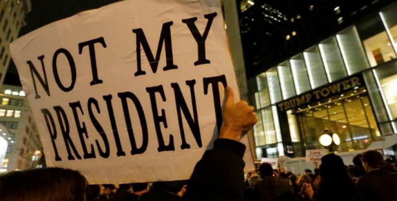 Un manifestante enseña cartel diciendo que Trump no es su presidente