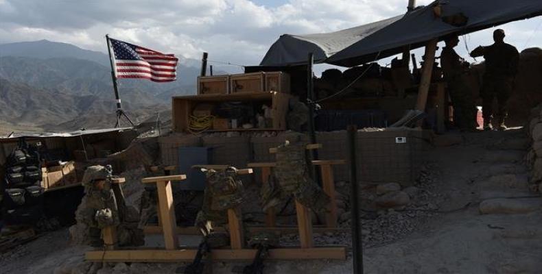 US Army soldiers from NATO look on as a US flag flies in a checkpoint during a purported patrol against the Takfiri Daesh terrorist group at the Deh Bala distri