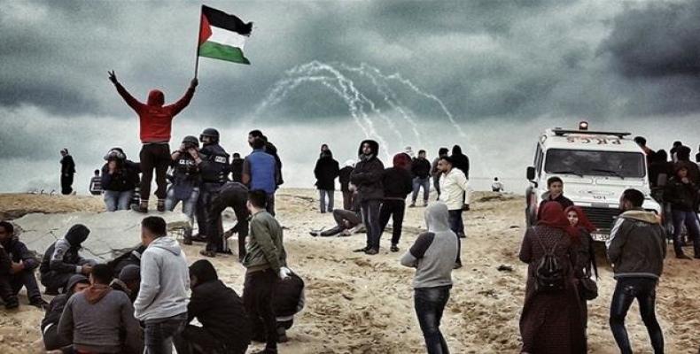 A Palestinian protester waves a national flag as people participate in a demonstration on the beach near the maritime border with the Israeli-occupied territor