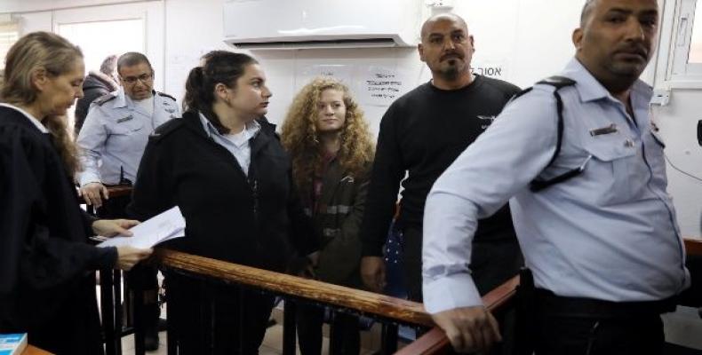 Palestinian teen Ahed Tamimi enters a military courtroom escorted by Israeli security personnel as her lawyer Gaby Lasky (L) stands near, at Ofer Prison, near t