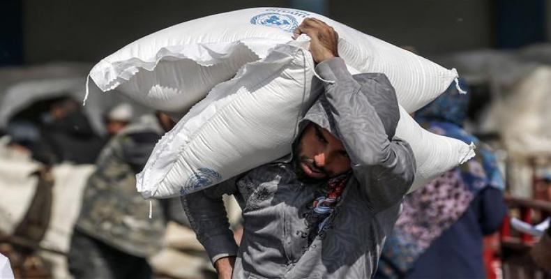 Palestinian man carries on his shoulder sacks of flour received from UNRWA in Gaza Strip. (Photo: AFP) Palestinian man carries on his shoulder sacks of flour received from UNRWA in Gaza Strip. (Photo: AFP)