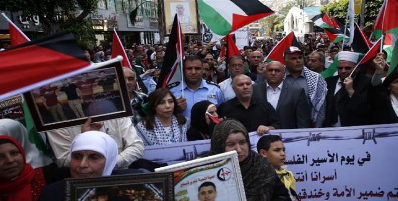 Palestinians hold portraits of relatives jailed in Israeli prisons as they protest to demand for their release during a demonstration to mark the Prisoners' Day