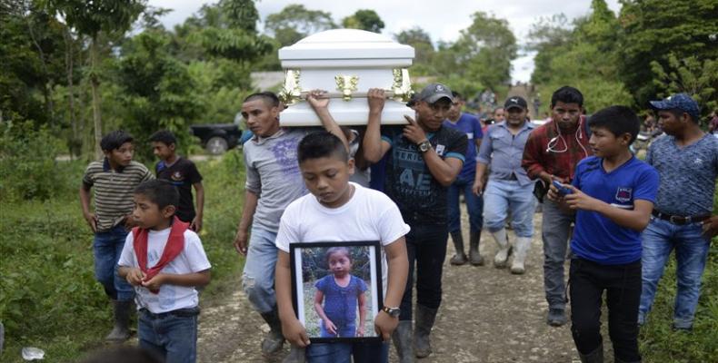 A boy carries a picture of Guatemalan seven-year-old Jakelin Caal, who died under US border patrol custody as her coffin is taken to the cemetery on December 25