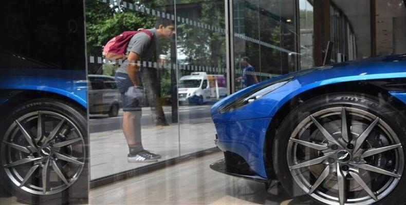 A pedestrian looks at a luxury car in a showroom in central London on August 29, 2018.  Photo: AFP