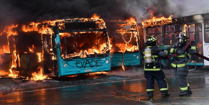 Bomberos extinguen las llamas de un autobús incendiado en Santiago de Chile, el 19 de octubre de 2019. / Martin BERNETTI / AFP