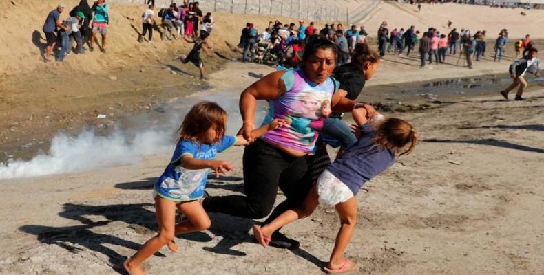 Maria Meza, a 39-year-old Honduran woman, runs with her two daughters as tear gas spreads.  Photo: Reuters