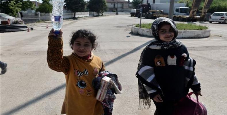 Two little girls hold bottled water and biscuits they received from villagers of Pythio after crossing the Evros River with the family from Syria. The river is