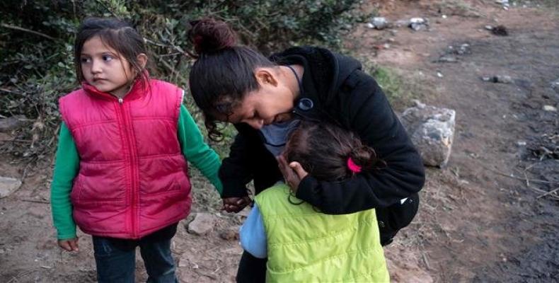 A Central American migrant travelling in a caravan, comforts her daughter as her group hesitates before attempting to cross the Mexico-US border fence to San Di