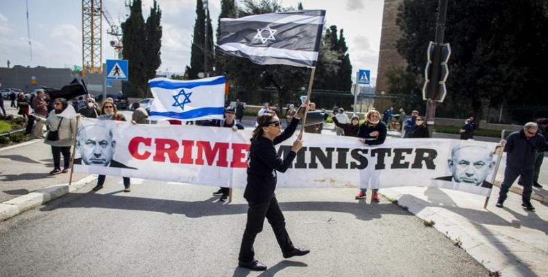 People wave Israeli flags and carry a banner reading 'Crime Minister' during a protest outside the Israeli parliament in Jerusalem.  (Photo: Eyal Warshavsky/AP)
