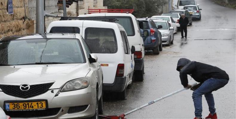 A Palestinian checks a car as vehicles with their tires slashed are pictured in the neighborhood of Shuafaat.  (Photo: AFP)