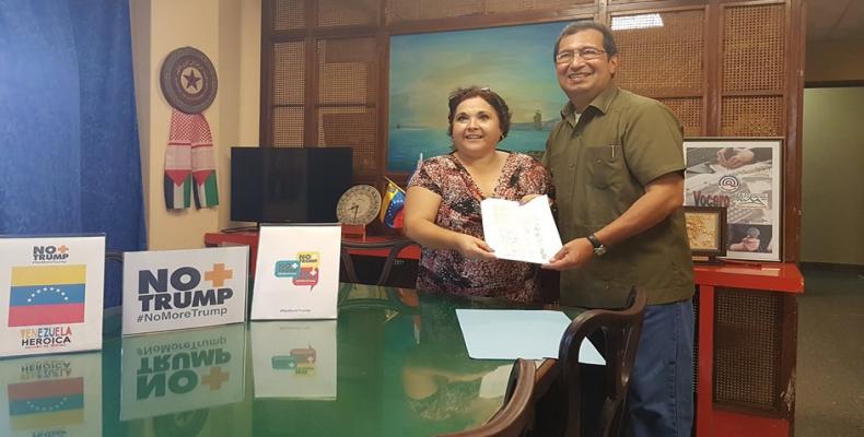 RHC´s Director, Tania Hernandez, hands over the book of signature to Venezuelan Ambassador, Adan Chavez Frias.
