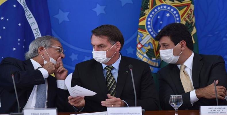 Economy Minister Paulo Guedes, left, speaks to Health Minister Luiz Henrique Mandetta, with President Bolsonaro in the middle.  (Photo: Andre Borges/AP Photo] [