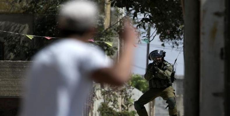 An Israeli soldier aims at a Palestinian protester following a weekly demonstration against the expropriation of Palestinian land by Israel in the village of Ka