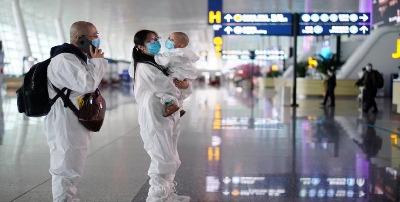 Travellers in protective suits are seen at Wuhan Tianhe International Airport in Wuhan